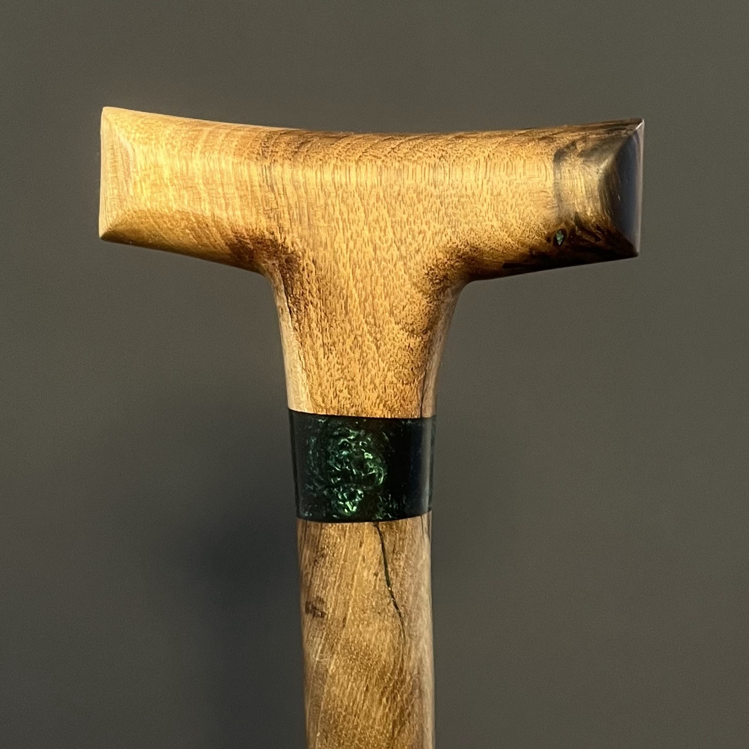 حلقه رزینی سبز‌رنگ روی بدنه‌ی چوبی عصا آرین