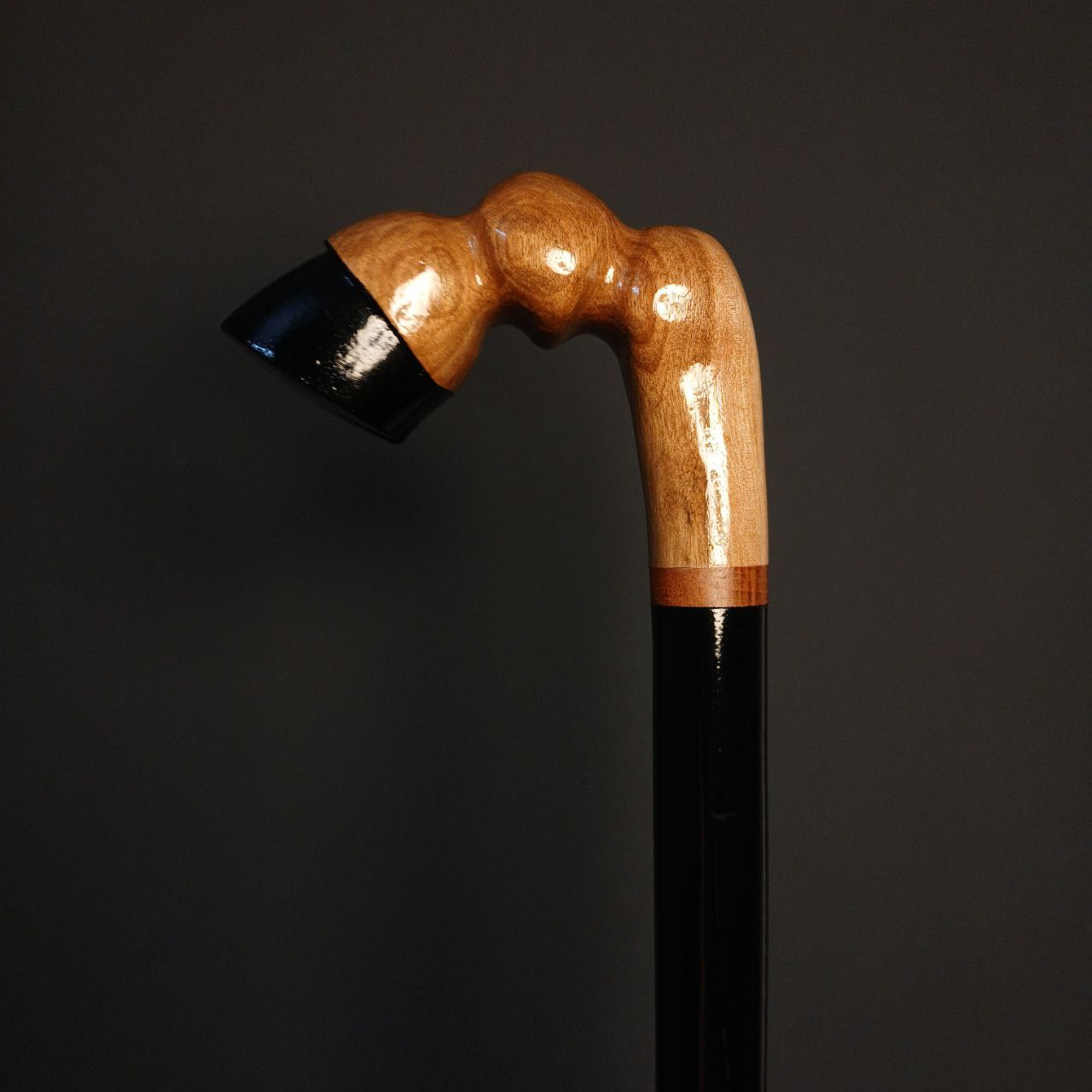 جزئیات بافت گردوی گیلان روی دسته و تضاد رنگ مشکی بدنه در عصای دست‌ساز طرح سم اسب.