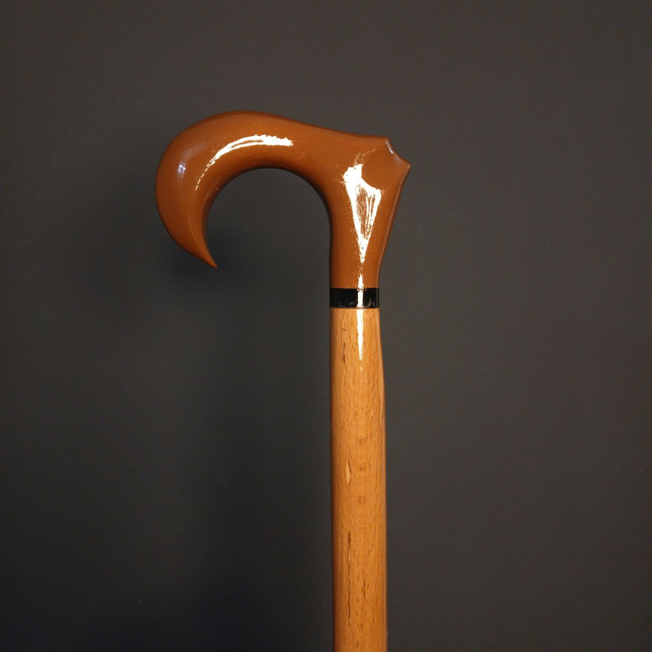 نمای نزدیک دسته ارگونومیک عصا دیبا، چوب گردوی گیلان با پرداخت کهربایی براق و حلقهٔ رزینی مشکی