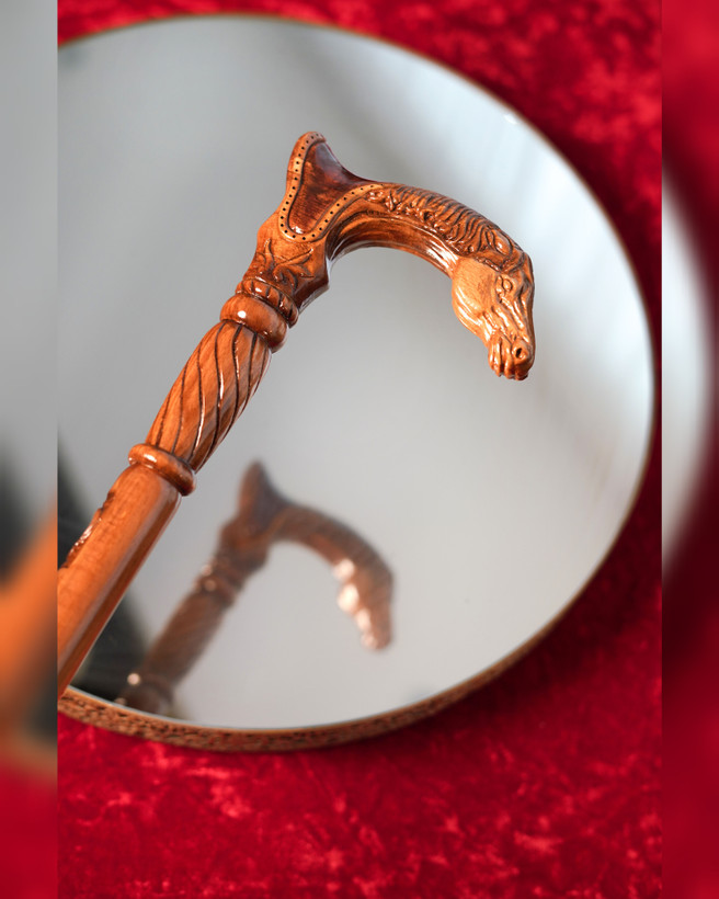 عکس نزدیک از دستهی منبتکاریشده عصا مدل رخش — سر اسب منبتشده روی چوب راش، پرداخت کهربایی براق.