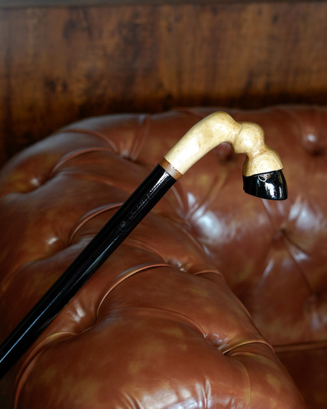 جزئیات بافت گردوی گیلان روی دسته و تضاد رنگ مشکی بدنه در عصای دستساز طرح سم اسب.