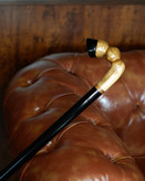 نمای نزدیک دسته پیکری عصا طرح سم اسب از چوب گردوی گیلان با رگههای طبیعی و بخشهایی رنگشده مشکی.