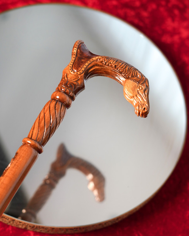 عکس نزدیک از دستهی منبتکاریشده عصا مدل رخش — سر اسب منبتشده روی چوب راش، پرداخت کهربایی براق.